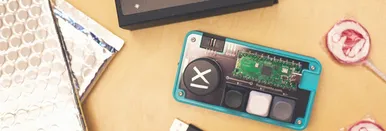 Material von GiftRush, dem Weihnachtsspiel von 9elements. Zu sehen ist die Verpackung des Spiels, zwei Lollipops, USB-Kabel sowie das selbst gebaute Pad.